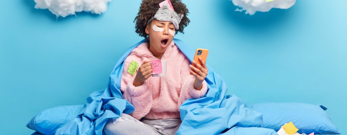 Eine Person in einem blauen Bett, umhüllt von einer Decke, schaut müde auf ihr Handy und hält eine Tasse in der Hand. Wolken mit Haftnotizen im Hintergrund.
